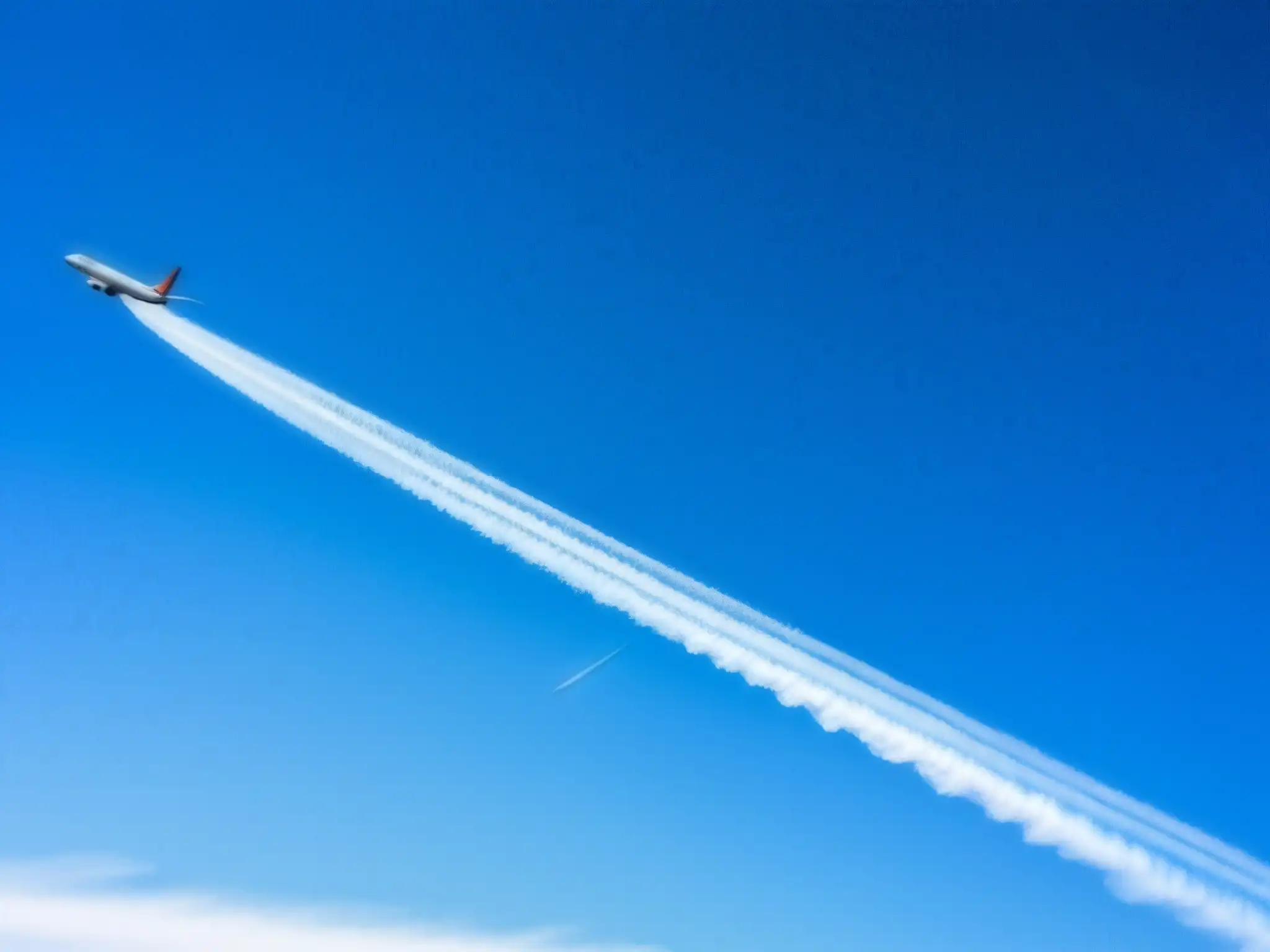 Avión comercial dejando largas estelas de condensación en el cielo azul